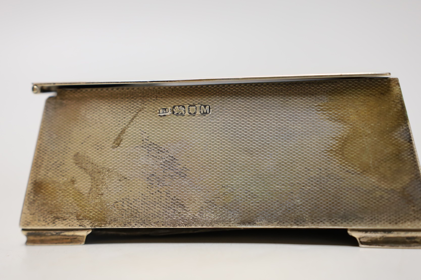 A George VI engine turned silver mounted cigarette box, of tapering rectangular form, the lid interior with engraved inscription relating to the Royal Hong Kong Golf Club, London, 1947, 17.7cm.